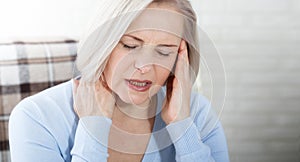 Woman suffering from stress or a headache grimacing in pain as she holds the back of her neck with her other hand to her