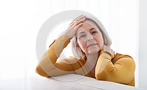 Woman suffering from stress or a headache grimacing in pain as she holds the back of her neck with her other hand to her