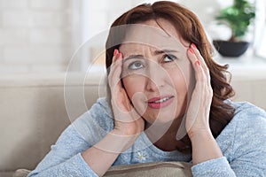 Woman suffering from stress or a headache grimacing in pain as s