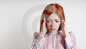 woman suffering from stress induced headache or migraine rubbing her temples with closed eyes