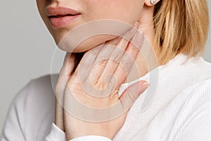 Woman suffering from throat problems, holding hands on her lymph nodes
