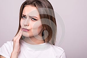 Woman suffering from toothache, tooth decay or sensitivity isolated on gray