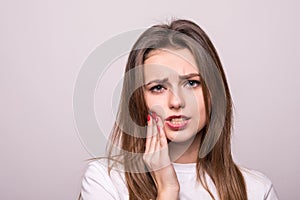 Woman suffering from toothache, tooth decay or sensitivity isolated on gray