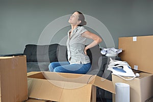 Woman suffers from back pain due to unpacking boxes