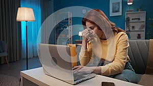 A woman suffers from a headache attack while working on a laptop while sitting on a sofa in the living room. The woman