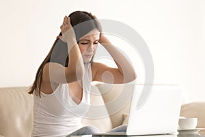 Woman suffers from headache during work on laptop