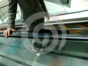 Woman in Suit Going Up the Escalator