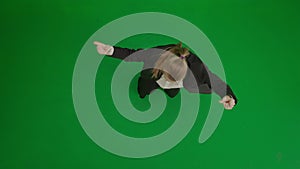 Woman in suit on green screen with chromakey. Blond businesswoman in formal outfit cheerfully dancing. Top view.