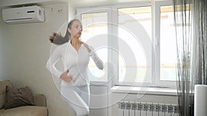 Woman in suit jogs in place training at home on sunny day