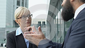 Woman in suit listening to inspired male colleague, discussing perspectives