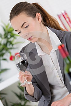 Woman in suit looking into glass red wine