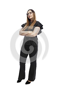 A woman in a suit stands with her arms crossed over her chest. Beautiful brunette in black trousers and a blouse. Business success
