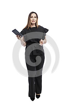A woman in a suit stands with a tablet in her hands. Beautiful brunette in black trousers and a blouse. Business success. Isolated
