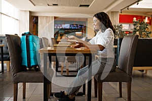 Woman with suitcase in cafe, airport waiting hall