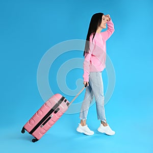 Woman with suitcase for summer trip on blue background. Vacation travel