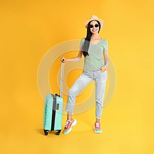 Woman with suitcase for summer trip on yellow background. Vacation travel