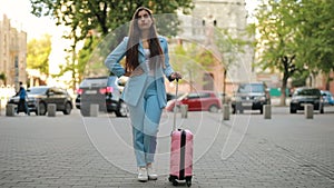 Woman with suitcase waiting taxi in a city