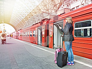 Woman with suitcases near train on station