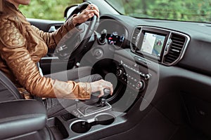 Woman in summer autumn, driving car, parking reversing, engages automatic transmission. Start movement of car, inclusion