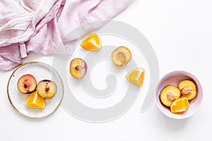 Woman summer breackfast with orange and peach fruits and fabric on white background flat lay