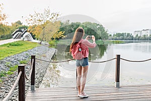 Woman summer in city near lake, river pond, photographing landscape smartphone, recording video to Internet, application