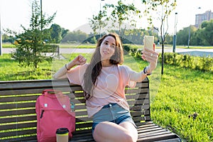 Woman in summer in a city park recording online video on phone, broadcasting social networks application on Internet