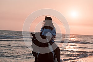 Woman in summer clothes enjoys riding a horse on a beautiful sandy beach at sunset. Selective focus