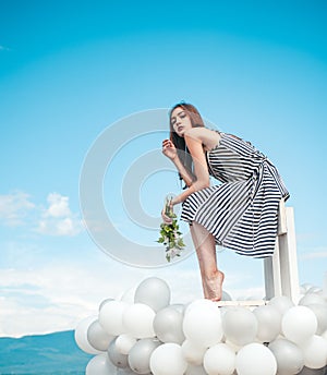 Woman in summer dress with party balloons. inspiration and imagination. girl with flowers sit in sky. feeling freedom