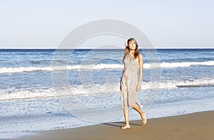 Woman In Summer Dress Walking Across Beach