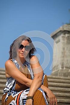 Woman in summer in the park with sun-glasses sits on stone steps