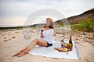 Woman in summer Picnic on the beach at sunset in the white plaid