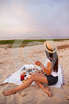 Woman in summer Picnic on the beach at sunset in the white plaid