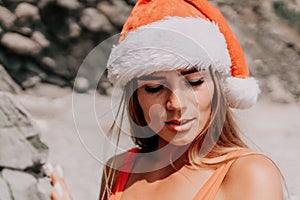 Woman summer travel sea. Happy tourist in red bikini and Santas hat enjoy taking picture outdoors for memories. Woman