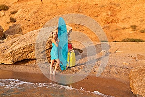 Woman on summer trip, suitcase and hat on sand. Board for sea surf. Idea of summer time, desire of adventure, copy space