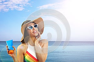 Woman with sun protection cream near sea, space for text