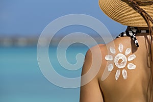Woman with sun-shaped sun cream on beach