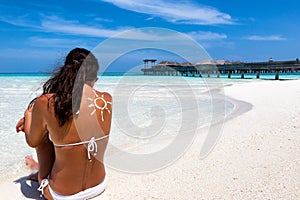 Woman with sun-shaped sunscreen drawing on her back