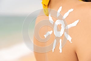 woman with sun-shaped suntan lotion on her shoulder, relaxing on the beach and taking care of her health. happy girl