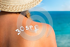 Woman with sun tan cream on her back over sea background