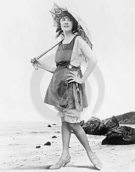 Woman with sun umbrella and bathing suit at the beach