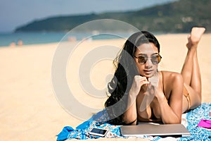 woman sunbathing on the beach with laptop mobile phone While relaxing on weekends