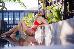Woman sunbathing in bikini at tropical travel resort. Beautiful young woman lying near pool.