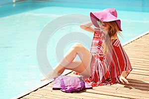 Woman sunbathing in bikini at tropical travel resort. Beautiful young woman lying on sun lounger near pool.