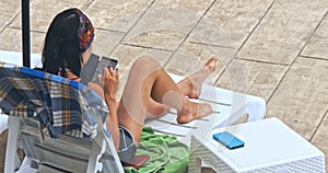 Woman sunbathing in chair by the pool