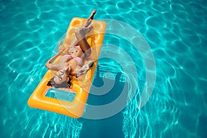 Woman sunbathing on mattress in swimming pool