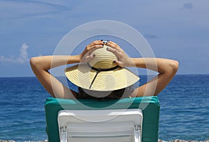 Woman sunbathing in a plastic chair on a beautiful