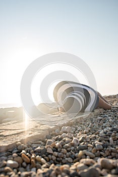 Woman sunbathing on a stony beach basking in the hot summer sun