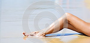 Woman sunbathing on tropical beach. Legs