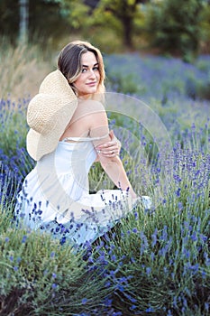 A woman in a sundress Enjoys the scent of Lavender. A girl in a sundress sits on a lavender field