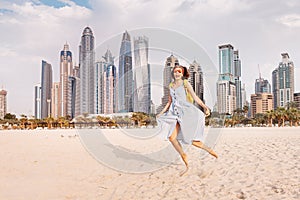 Woman in a sundress jumping with a background of huge skyscrapers in Dubai